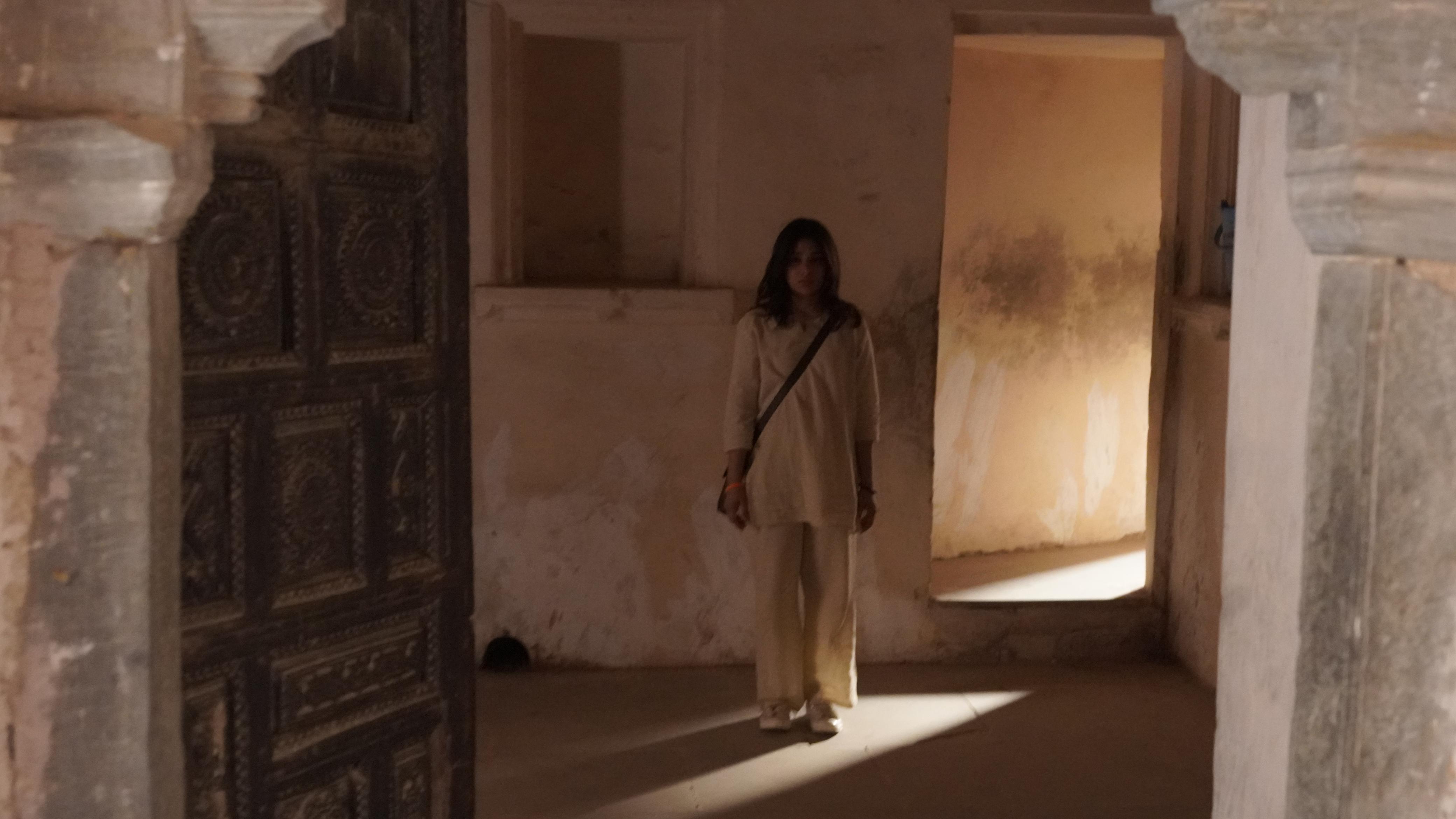 Khushi Solanki standing in a warm, light-filled stone corridor